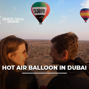 Hot air balloon flying over the Dubai Desert at sunrise with panoramic dune views.